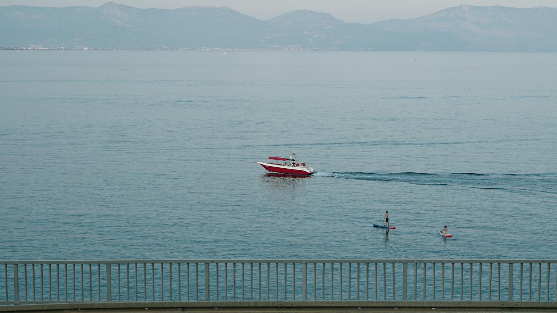 Motorówka i paddleboardziści na spokojnym jeziorze u podnóża Alp