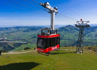 Czerwona kolejka linowa nad zielonymi krajobrazami Ebenalp w